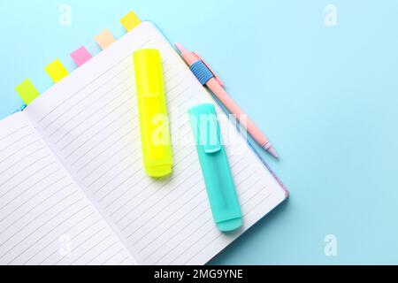 Notebook with sticky notes, markers and pen on color background Stock Photo