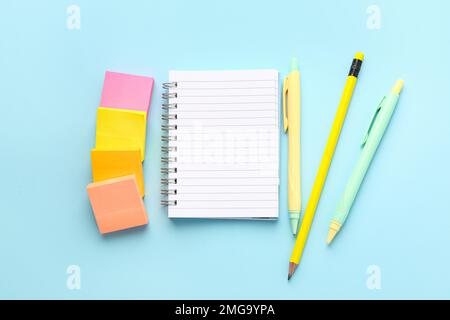 Notebook, sticky notes, pencil and pens on color background Stock Photo