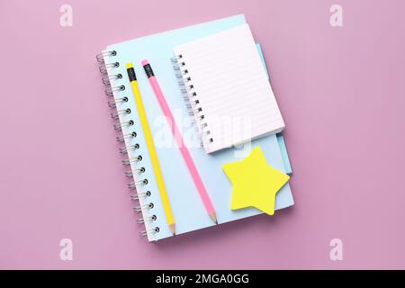 Notebooks, pencils and sticky notes on lilac background Stock Photo