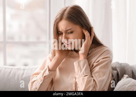 Irritated young woman suffering from loud noise at home, closeup Stock Photo