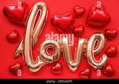 Balloon in shape of word LOVE among heart shaped ones on color background. Valentine's Day celebration Stock Photo