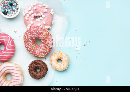 Parchment with different delicious donuts on blue background Stock Photo
