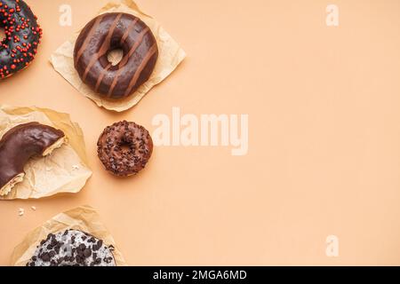 Parchments with different delicious donuts on beige background Stock Photo