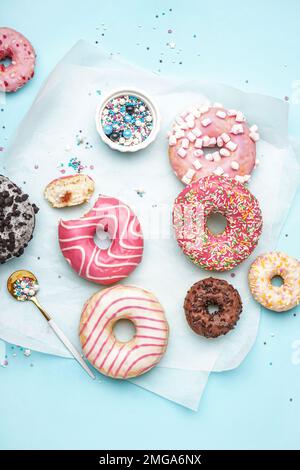 Parchment with different delicious donuts on blue background Stock Photo