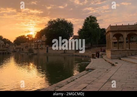 Beautiful sunset at Gadisar lake, Jaisalmer, Rajasthan, India. Setting sun and colorful clouds in the sky with view of the Gadisar lake. Stock Photo