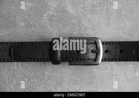 Black men leather belt with metal badge gray concrete background Stock Photo
