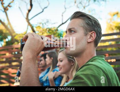 The weekend is going down well. a young man drinking beer with his friends in the background. Stock Photo