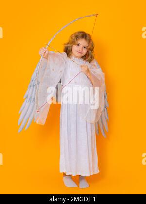 Child cupid hold bow and arrow. Kid wearing angel costume white dress and feather wings. Innocent child. Stock Photo