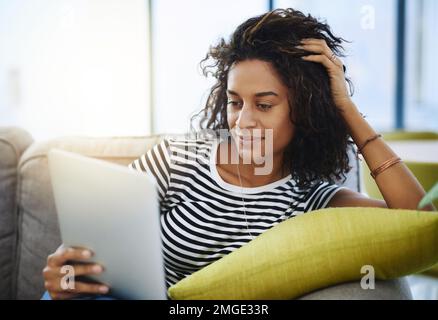 Can finally check out apps. an attractive young woman relaxing at home on the weekend. Stock Photo