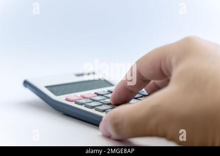 Hand calculating with a white digital calculator isolated on white background. Calculator with Solar and battery function. Business, financial. Stock Photo