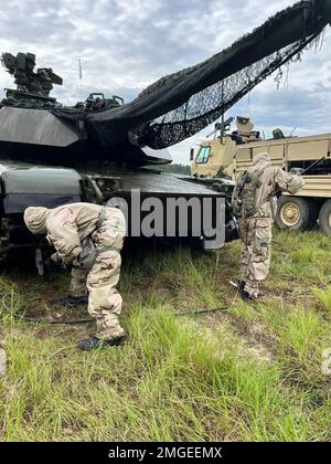 U.S. Army Chemical Corps Soldiers assigned to the 83rd Chemical Battalion mop the tracks of a modernized M1A2 SEPv3 Abrams tank, assigned to the 'Mustang Squadron,' 6th Squadron, 8th Cavalry Regiment, 2nd Armored Brigade Combat Team, 3rd Infantry Division, with a cleaning solution during a joint decontamination exercise on Fort Stewart, Georgia, Aug. 24, 2022. Chemical, biological, radiological and nuclear skills, such as decontamination, exist to enable movement and maneuver to conduct large-scale ground combat operations in a CBRN environment. Stock Photo