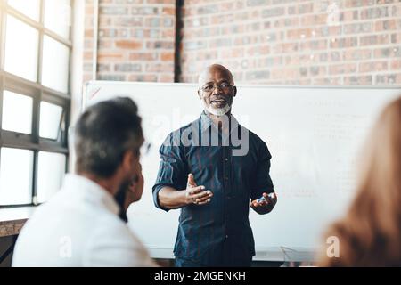 I always keep my meetings sharp and on point. a businessman giving a presentation to his colleagues in a boardroom. Stock Photo