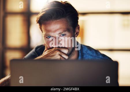 Thinking carefully before making his next move. a handsome young male designer looking thoughtful while working late in his office. Stock Photo