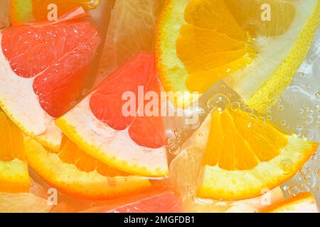 Slices of grapefruit, orange and pomelo in water on white background. Pieces of grapefruit, orange fruit and honey pomelo in liquid with bubbles. Slic Stock Photo