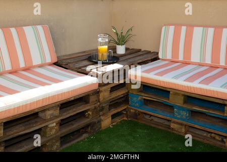 recycled wooden bench made from old wood storage pallet diy with cushions on home garden terrace Stock Photo