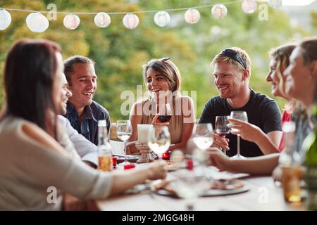 Good times with the gang. a group of happy young friends sharing a meal at a backyard dinner party. Stock Photo