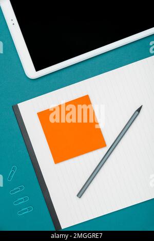 Mobile Phone Lying on Desk. Important infrormation written on colored paper and notebook. Different Office Supplies, Pencils, Pens, Marckers. Computer Stock Photo