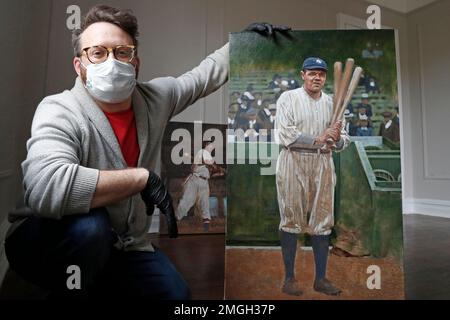 In this April 29, 2020, photo, baseball artist Graig Kreindler poses with his unfinished painting of Babe Ruth, right, as a painting of Josh Gibson rests behind him at his residence in the Brooklyn borough of New York. Over 200 of Kreindler's paintings of Negro Leagues players were on exhibit at the Negro Leagues Baseball Museum in Kansas City, Mo., when the coronavirus pandemic caused the museum to close. (AP Photo/Kathy Willens)