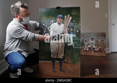In this Wednesday, April 29, 2020, photo, baseball artist Graig Kreindler points out areas of his unfinished painting of Babe Ruth that need more work as he holds the painting upright at his residence in the Brooklyn borough of New York. Over 200 paintings by Kreindler are currently on display at the Negro Leagues Baseball Museum in Kansas City, Mo., which closed in mid-March due to concerns over the spread of the new coronavirus. The museum aims to reopen in June. (AP Photo/Kathy Willens)