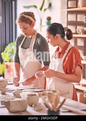 Pottery, ceramic and teacher with student in workshop training, learning and sculpture class production. Clay design, mentor and creative women or Stock Photo