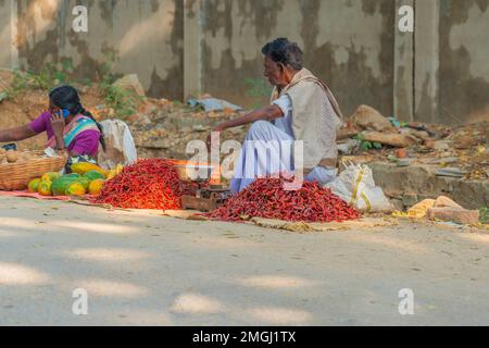 Puttaparthi, Andra Pradesh - India - January 21.2023: A man selling red chili pepers, sitting on the street at a local Indian market Stock Photo