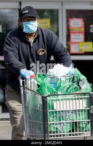 A shopper leaves Village Market Place grocery store as he wears a face mask  and gloves in Skokie, Ill., Thursday, April 16, 2020. In an effort to slow  the spread of the