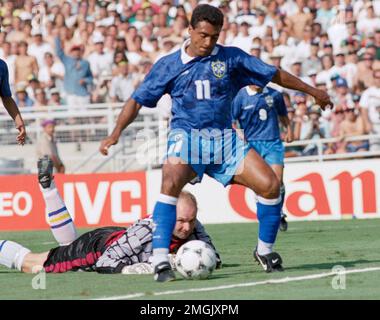 Swedish goalie Thomas Ravelli watches Brazilian forward Romario dribble ...