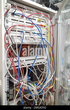 in the server rack many different colored network cables are connected to the network switches Stock Photo