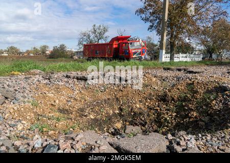 Damaged truck stands on the side of the road. In the foreground is an explosion crater. War in Ukraine. Russian invasion of Ukraine. War crimes Stock Photo