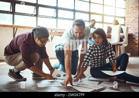We find and fix problems together. a team of entrepreneurs collaborating and sitting on the floor in a modern office. Stock Photo