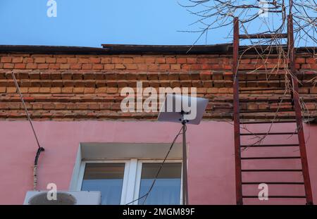 Starlink satellite dish, an internet constellation operated by SpaceX, is installed on the wall of an apartment building. Stock Photo