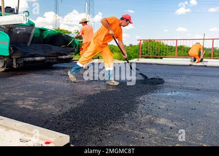 Zrenjanin, Vojvodina, Serbia - June 8, 2021: View on machine for laying asphalt, spreading layer of hot tarmac on prepared ground a few workers are us Stock Photo