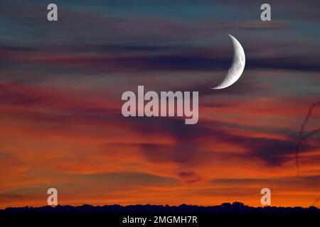 Crescent moon in the clouds at sunset, Doubs, France Stock Photo