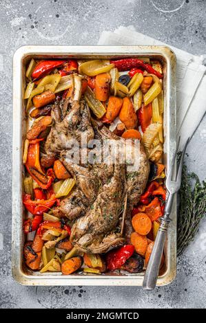 Roast lamb mutton shoulder meat in a baking dish with vegetables. Gray background. Top view Stock Photo