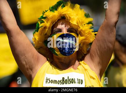 A woman covers her face with a Brazilian flag during rally supporting Brazil's President Jair Bolsonaro on Copacabana beach, Rio de Janeiro, Brazil, Sunday, March 15, 2020. Thousands took to the streets on Sunday to demonstrate in favor of Bolsonaro, challenging in some states the ban on agglomerations due to coronavirus and ignoring his suggestion to postpone the acts. (AP Photo/Silvia Izquierdo)