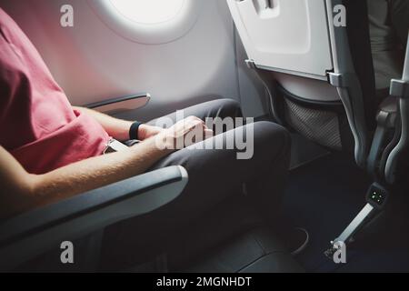 Man resting during flight. Legroom between seats in commercial airplane. Stock Photo