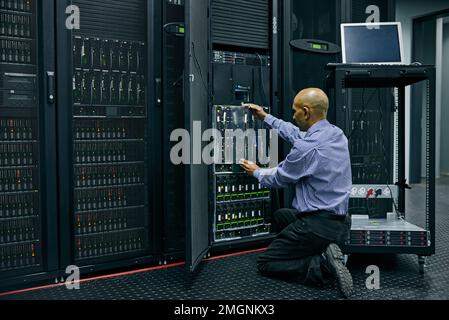He knows his way around a computer system. an IT technician repairing a computer in a data center. Stock Photo