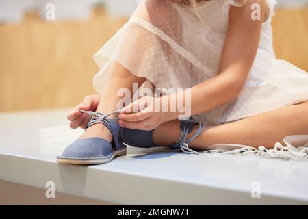 Hands, little girl and tying shoe lace on table getting ready for walk, travel or shopping at home. Hand of child, kid or toddler trying to tie shoes Stock Photo
