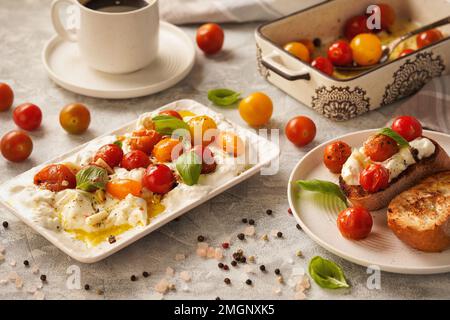 Lunch idea - burrata cheese with baked tomatoes and toasts. Stock Photo