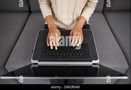 Female programmer coding on laptop at home. BIPOC woman typing text on notebook keyboard in overhead closeup photo Stock Photo
