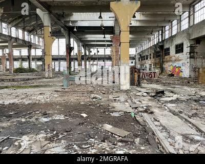 Interior of abandoned industrial hall from an old factory full of mess. Brownfield with broken windows and damaged and sprayed walls. Stock Photo