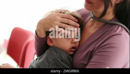 Tired child on mother lap in the verge of napping kid falling asleep Stock Photo