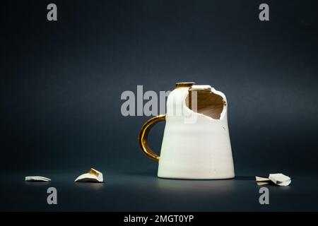 Broken tea cup isolated on black background. Cracked coffee mug and fragile ceramic pieces Stock Photo