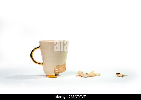 Broken tea cup isolated on white background. Cracked coffee mug and fragile ceramic pieces Stock Photo