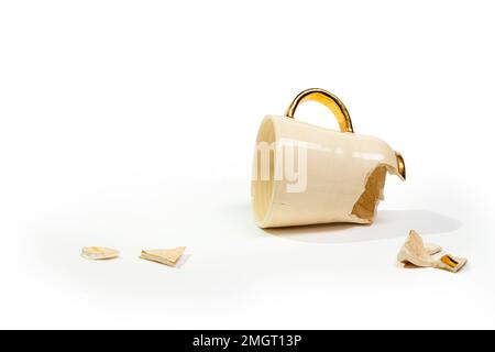 Broken tea cup isolated on white background. Cracked coffee mug and fragile ceramic pieces Stock Photo