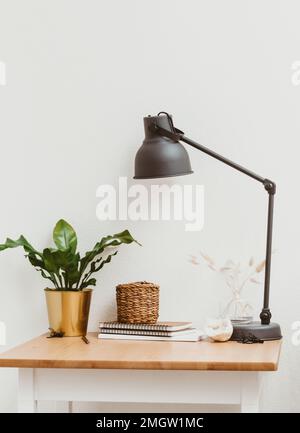 Living room interior with wooden table, white flowers in vase, metal lamp in modern home decor. Copy space. Front view Stock Photo