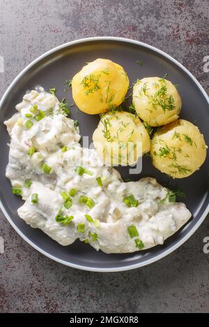 Sahnehering is a German dish with pickled Herrings fillets, apples and onion in a spiced marinade of cream served with boiled potato closeup on the pl Stock Photo