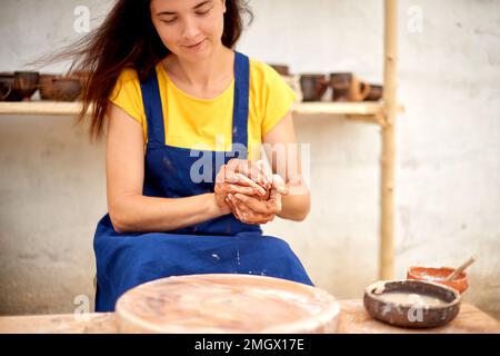 making sphere shape from clay for manufacture of pottery product. woman working with pottery wheel Stock Photo