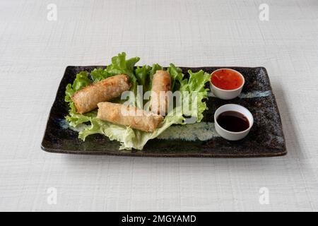 Thai dishe culinary Still Life. Spring rolls with salad accompaniement and spicy sauce Stock Photo