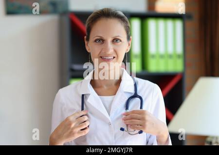 Happy female doctor with stethoscope looking at camera in medical office. Stock Photo